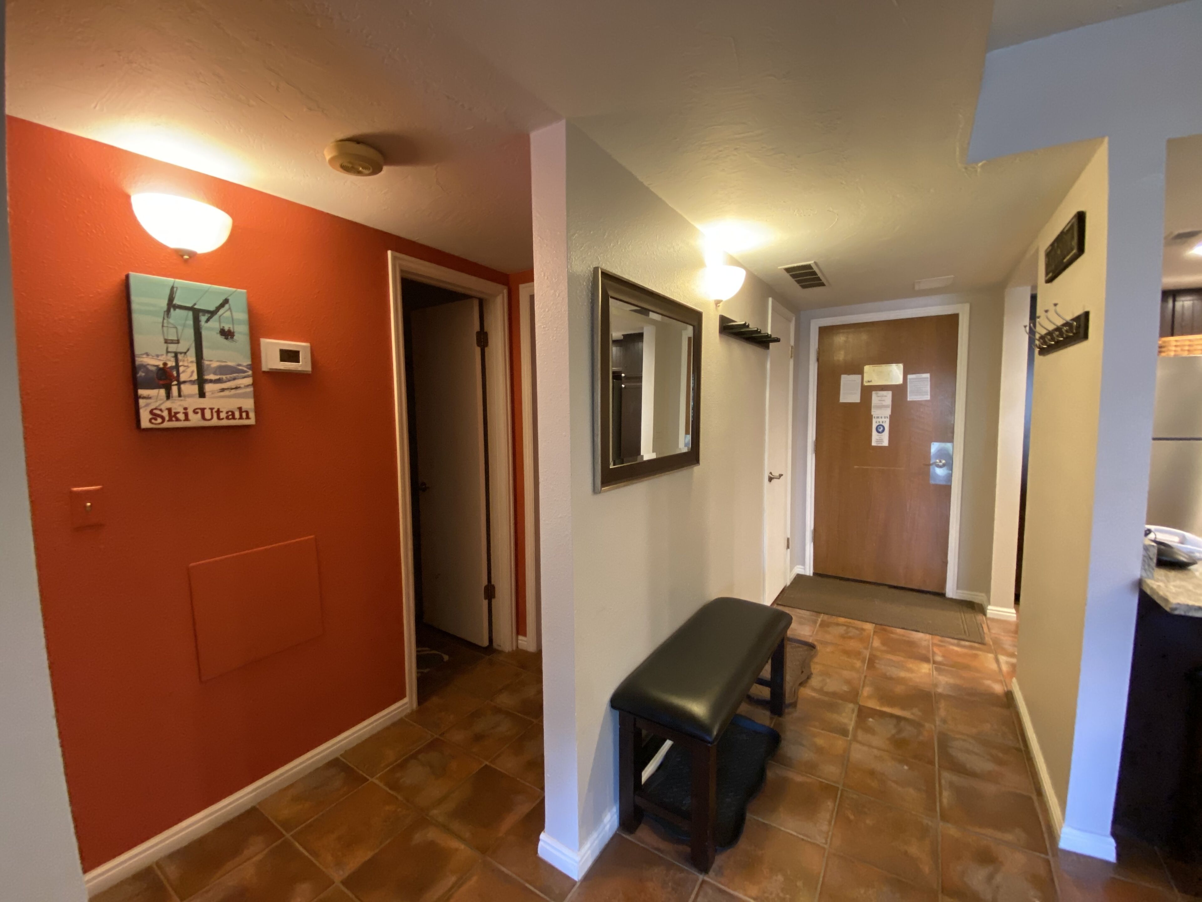 A hallway with a bench, a door with a sign, and a wall with a picture.