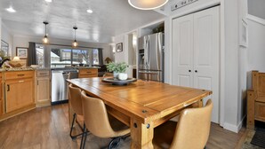 Een moderne keuken met een houten eiland, roestvrijstalen apparatuur en hangende lampen.