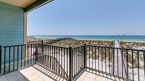 Un balcón con vista a una playa y un paseo marítimo de madera.