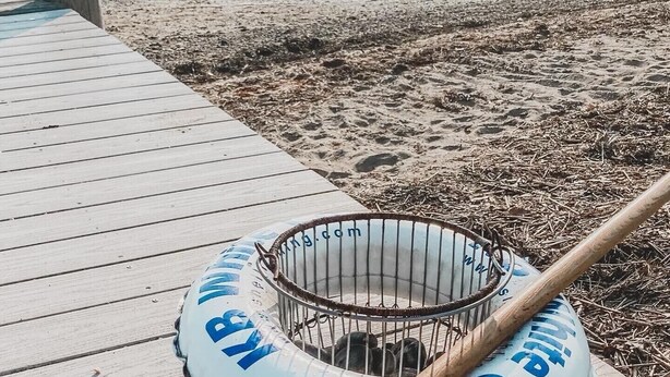 A beach scene with a wooden boardwalk, a metal basket, and a floating object with text.