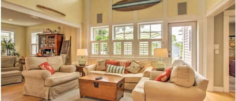 A spacious living room with high ceilings, large windows, and a cozy seating area with a coffee table.