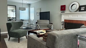 Una sala moderna con un sofá, un sillón y una chimenea.