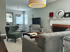 A modern living room with a sofa, armchair, and a fireplace.