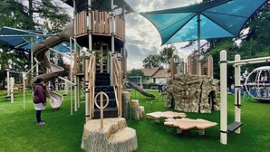 Un parque infantil con tobogán, estructuras para escalar y mesas de picnic.