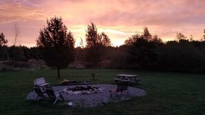 A backyard with a fire pit, two chairs, and a picnic table. - Controlled Chaos Basecamp - centered between Jackson & Clark County Trail System (Merrillan)