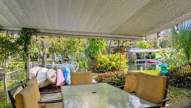 Un espace extérieur aménagé avec des tables et des chaises, entouré de verdure et offrant une vue sur un plan d’eau.