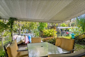 Een terras met tafels en stoelen, omringd door groen en uitzicht op een waterlichaam.