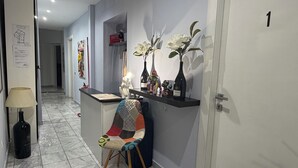 Een moderne hal met een bureau, een stoel en decoratieve objecten zoals vazen en een lamp.