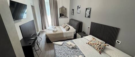 Une chambre d’hôtel moderne, équipée de deux lits, d’un bureau, d’une chaise, d’une télévision et ornée d’œuvres d’art sur les murs.