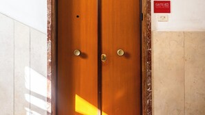 Een houten dubbele deur met een rode mat waarop ‘GATE 40’ staat, die naar een kamer leidt.