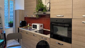 Een moderne keuken met houten kastjes, een magnetron, een oven en een potplant.