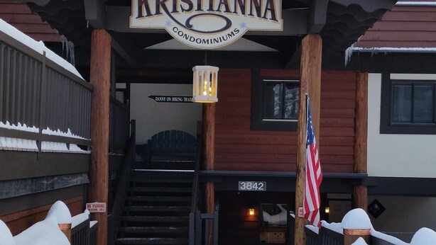 A building named Kristianna Condominiums with a covered entrance, steps leading up to it, and an American flag.