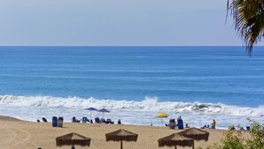 Una playa con sombrillas y sillas, cielo despejado y el océano.