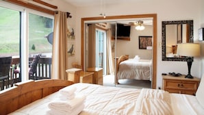 A hotel room with a bed, a desk, a chair, a mirror, and a window with a view of the outdoors.