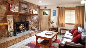 A cozy living room with a stone fireplace, a leather sofa, and a coffee table.