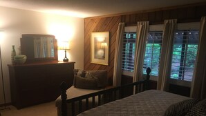 A bedroom with a bed, a dresser, a lamp, and a window with curtains. - FALLING WATERS ~ 2b/2b SPECTACULAR VIEW HANGING OVER FALLS, UPSCALE FURNISHINGS. (Lake Toxaway)