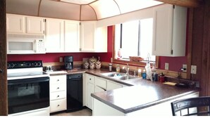 A compact kitchen with white cabinets, a microwave, a stove, and a sink. - FALLING WATERS ~ 2b/2b SPECTACULAR VIEW HANGING OVER FALLS, UPSCALE FURNISHINGS. (Lake Toxaway)