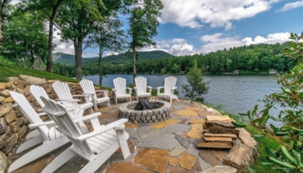 Relax by the water's edge in this serene outdoor seating area, featuring a fire pit and Adirondack chairs.