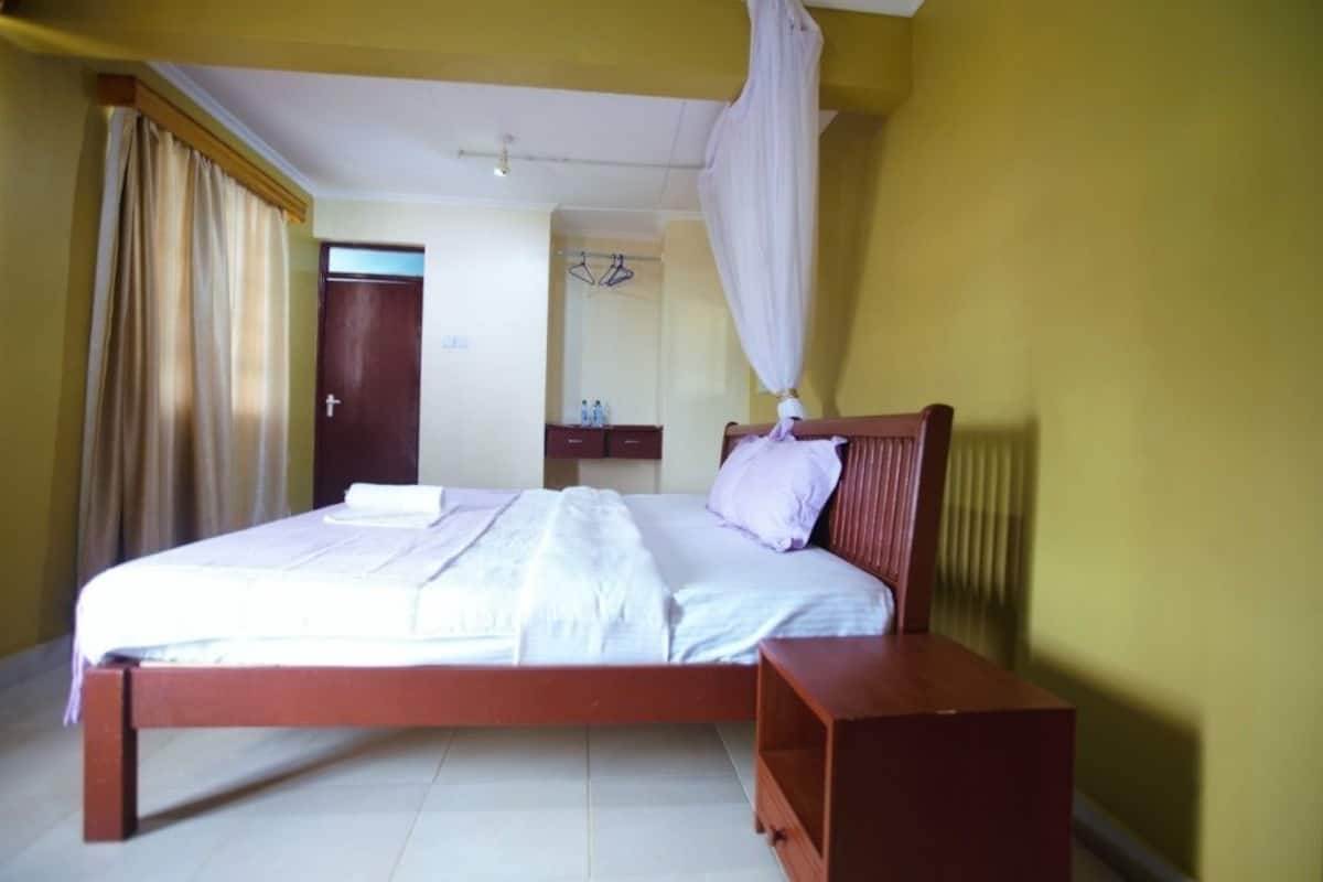 A bedroom with a bed, a bedside table, a wardrobe, and a curtain.