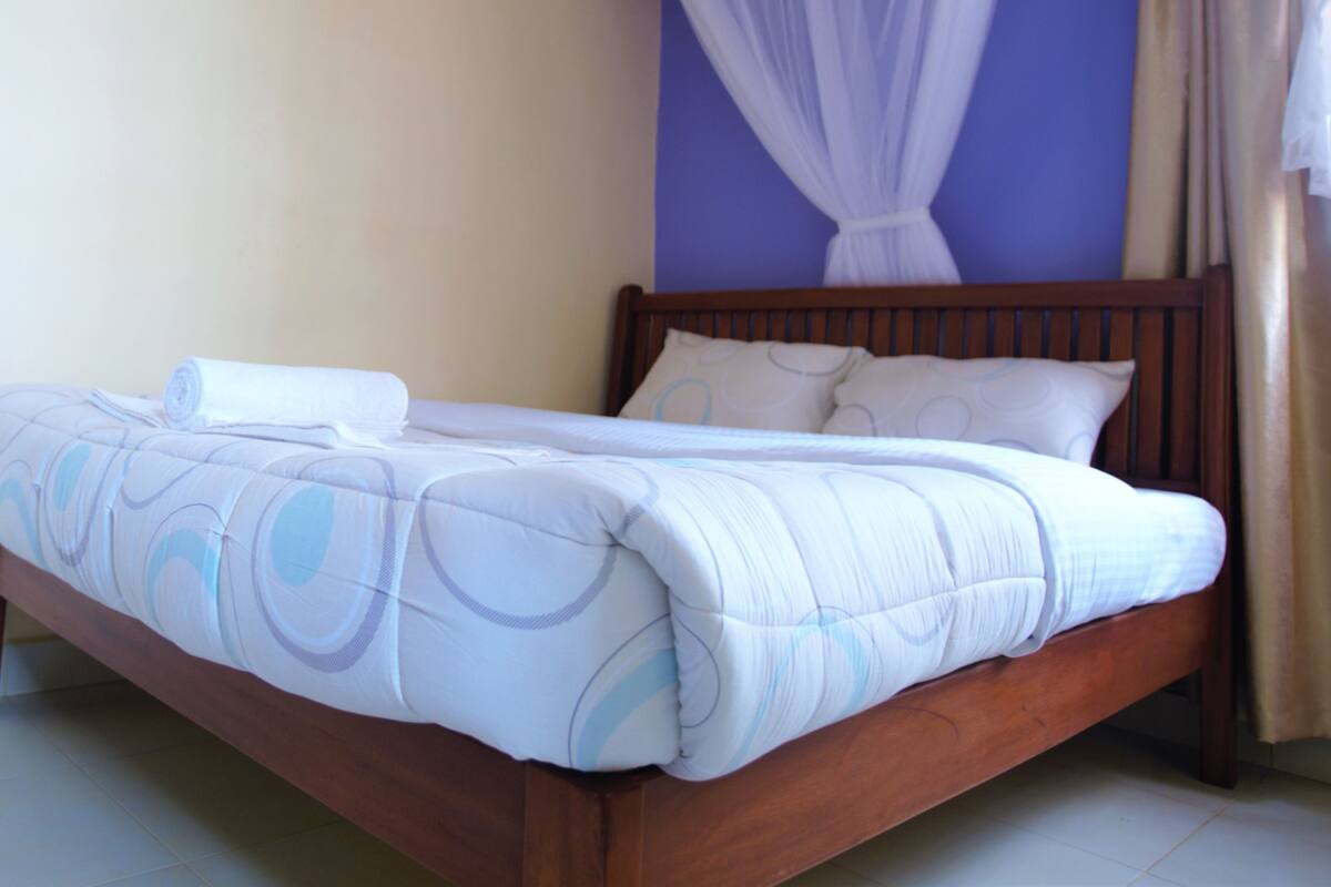 A bed with a canopy, a pillow, and a rolled towel.