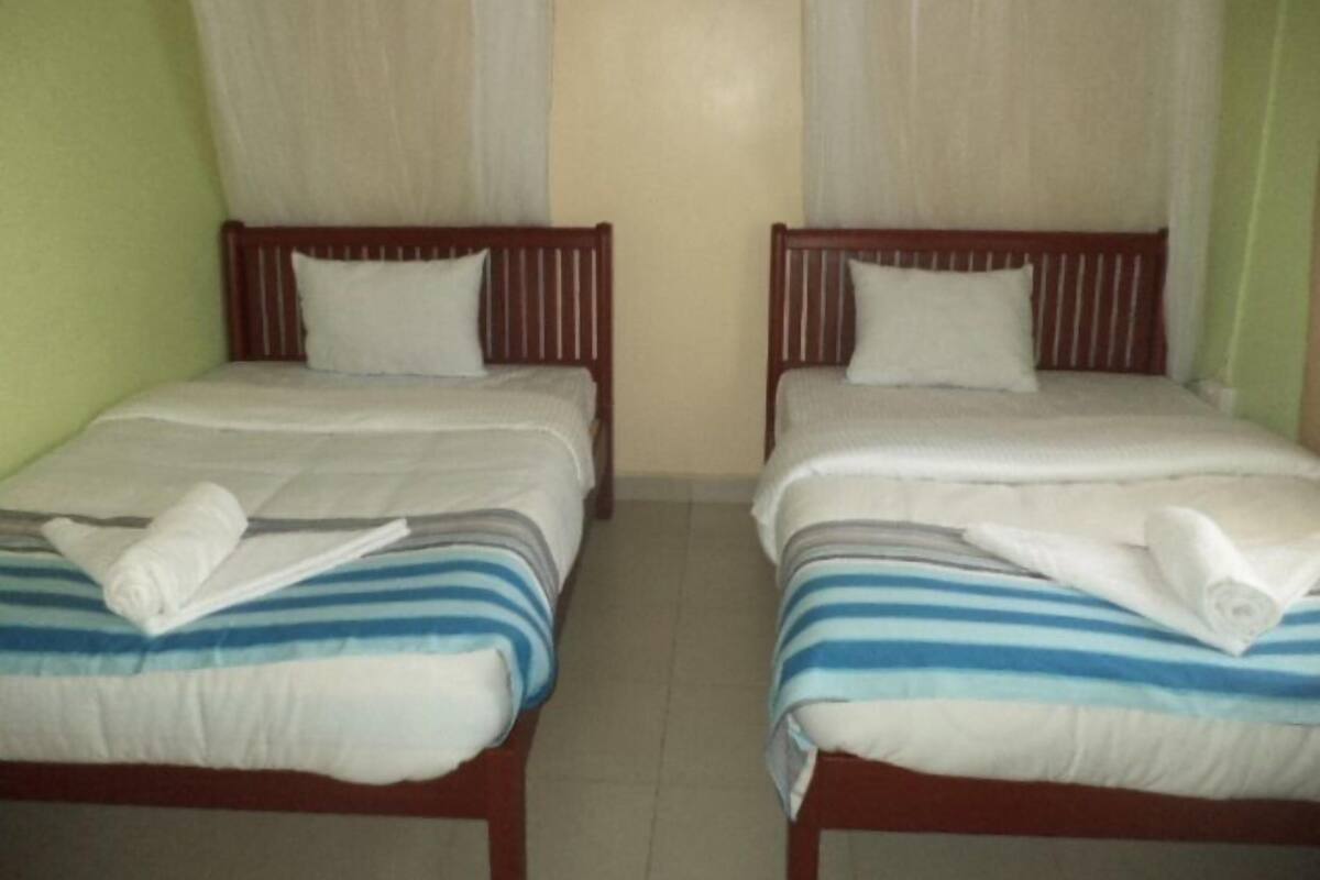 Two single beds with wooden frames, white bedding, and striped blue and white covers.
