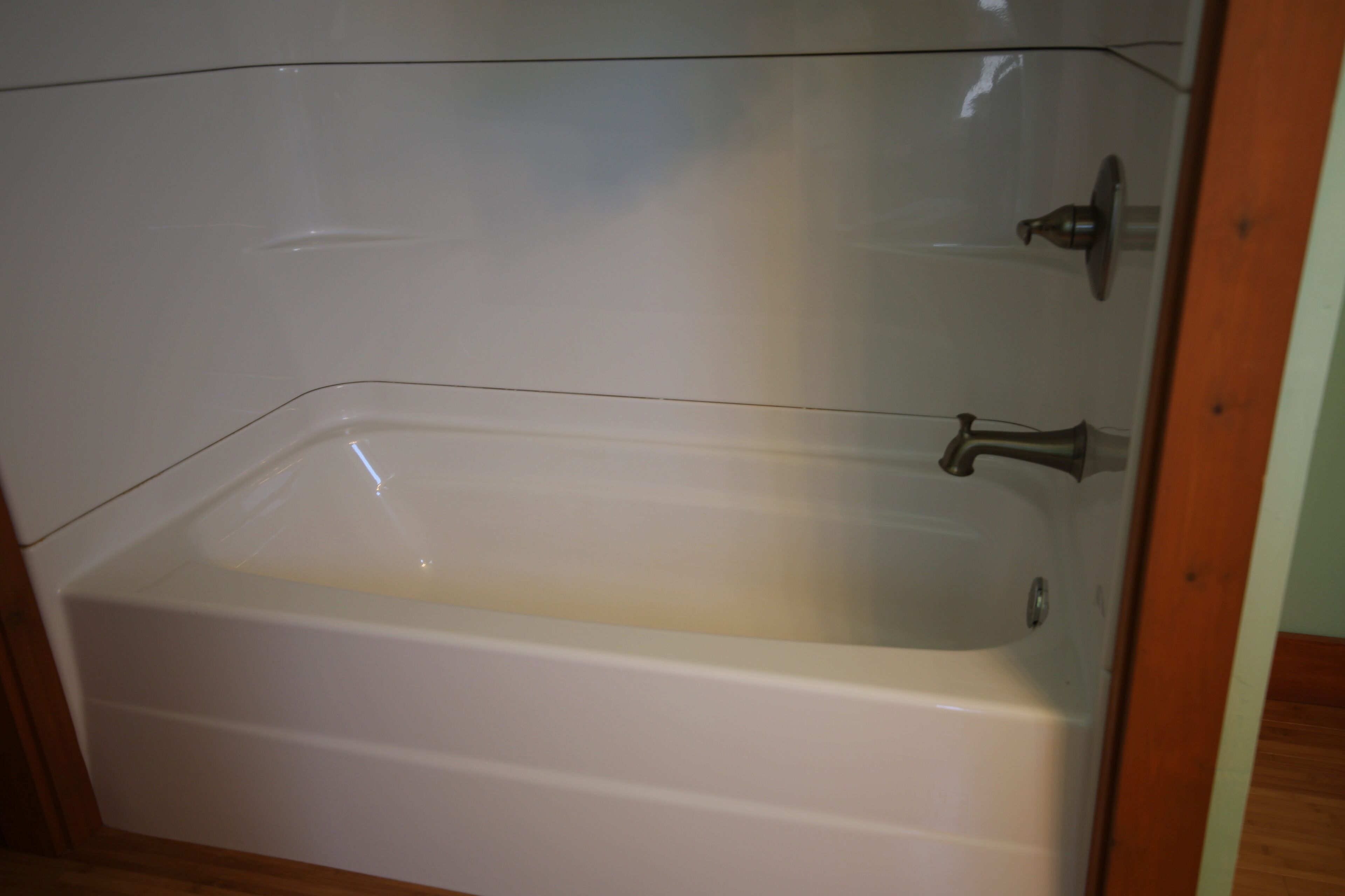 Una bañera blanca con grifo y ducha, frente a una pared de azulejos.
