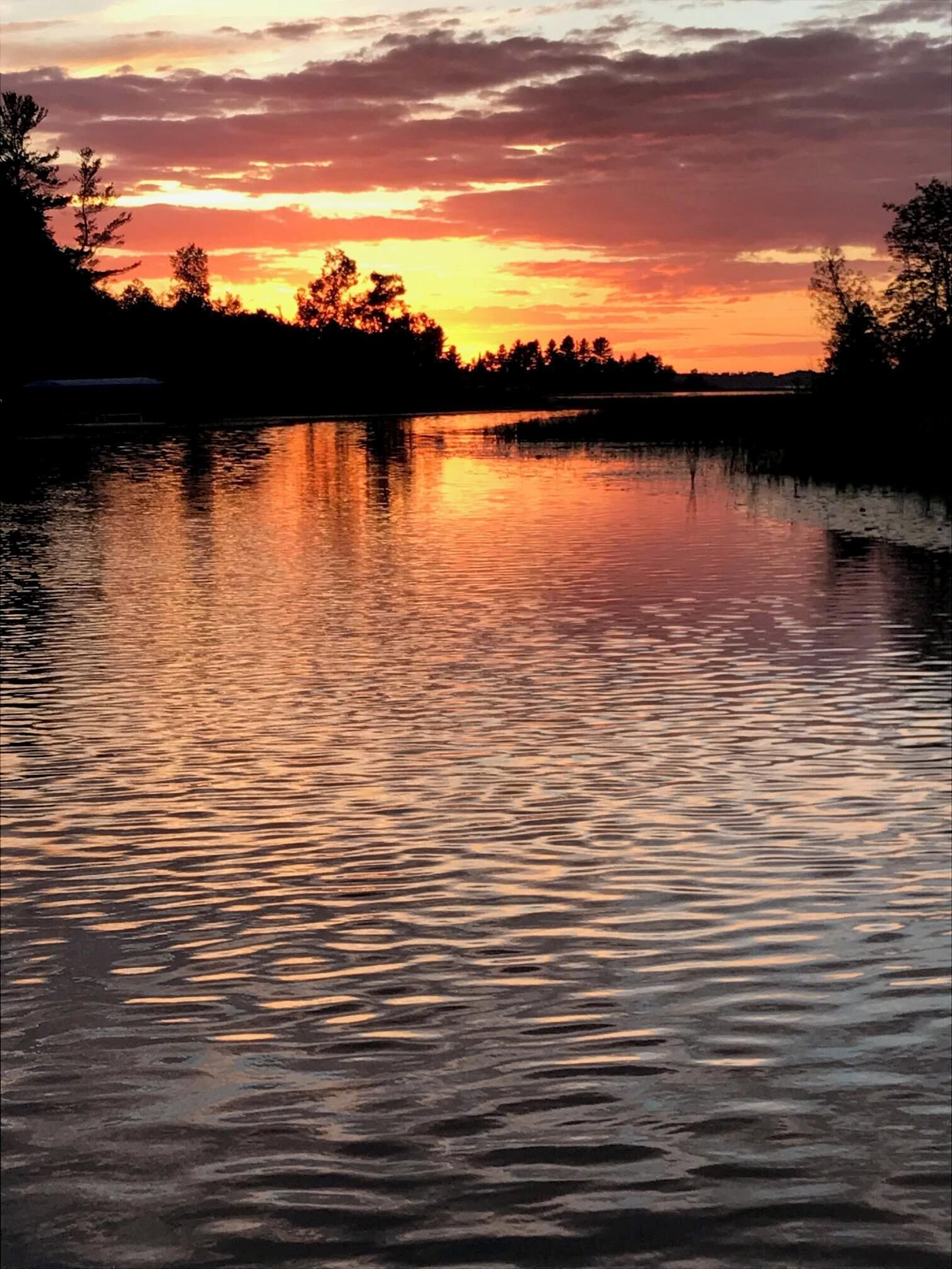 Una superficie acuática tranquila reflejando un cielo al atardecer.