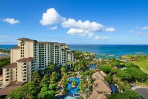 A resort with a large building, a swimming pool, and a view of the ocean.
