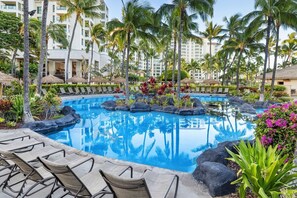 A pool area with lounge chairs, palm trees, and a reflection pool.