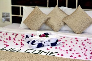A neatly made bed with a 'WELCOME' sign, decorative pillows, and a bouquet of flowers. - Holiday Home Kelaa (Kelaa)