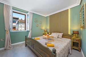 A bedroom with a bed, bedside tables, a window with curtains, and decorative wall art.