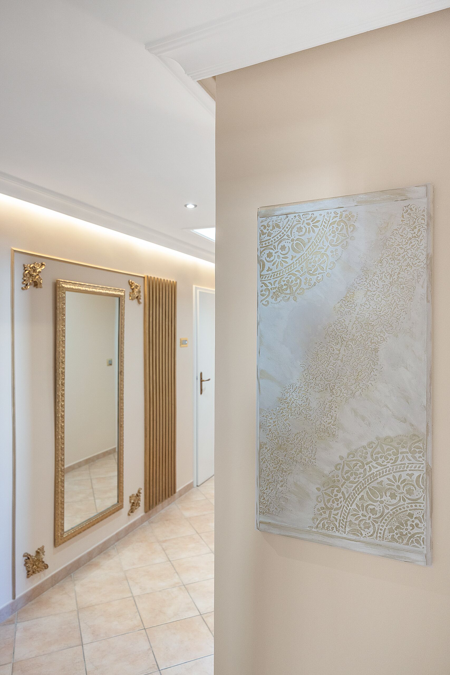 A hallway with a large mirror, a decorative wall piece, and a door.