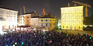 A crowded square with buildings and a construction crane in the background.