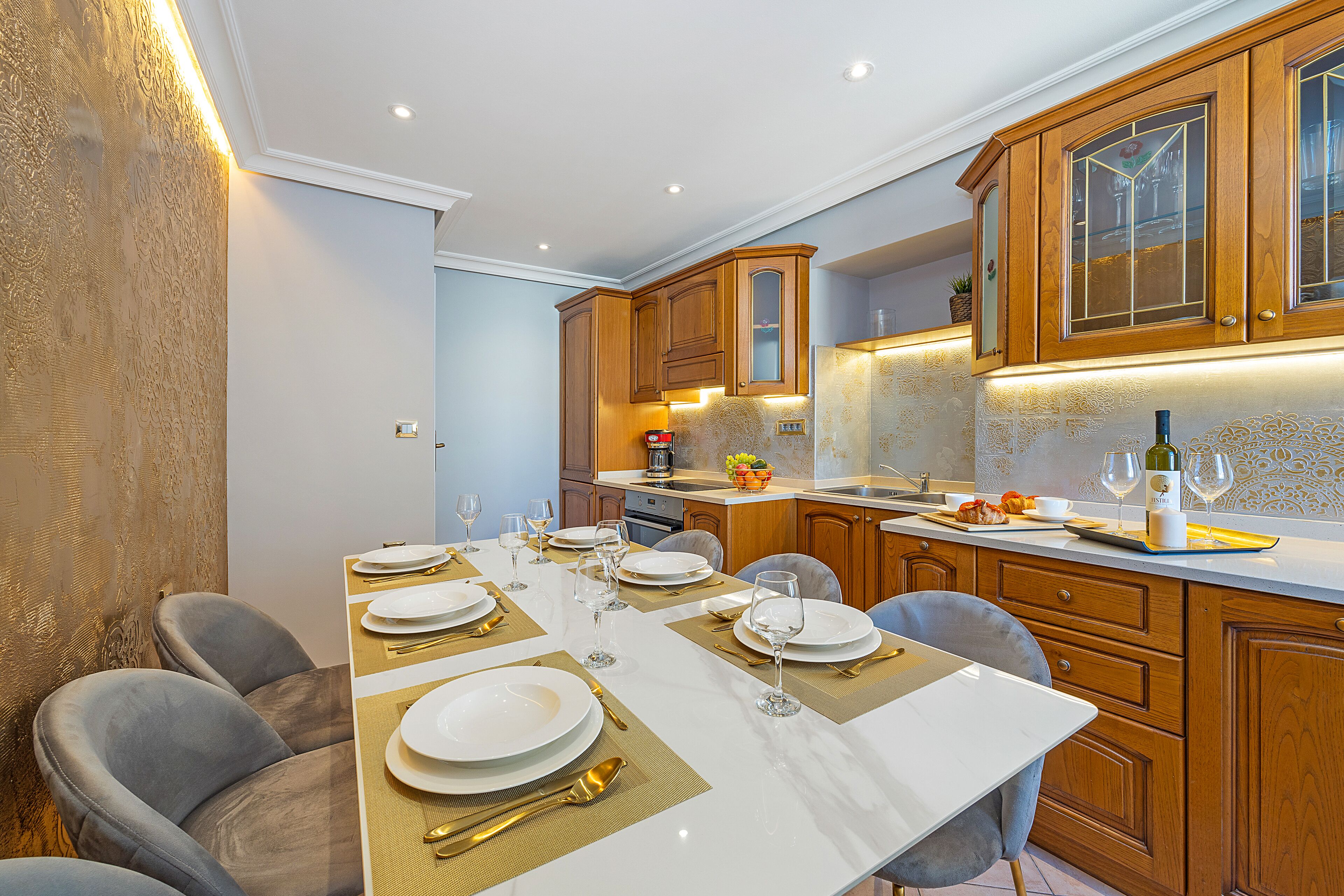 Une cuisine moderne avec des meubles en bois, un plan de travail en marbre et un coin repas aménagé pour six personnes.