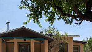 A two-story house with a stone foundation, a front porch, and a small tree in the yard.