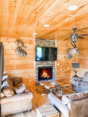 Een knus interieur van een chalet met een stenen openhaard, houten wanden en twee leren banken.