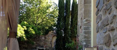 Un edificio in pietra con un vialetto in pietra che conduce a una zona con sedute, sedie e un tavolo.