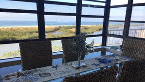 Un comedor con sillas de mimbre, una mesa de vidrio con mantel de estrella de mar y una escultura decorativa de pez.