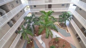 Un atrium à plusieurs niveaux, doté de balcons, de palmiers et d’un espace paysager central.