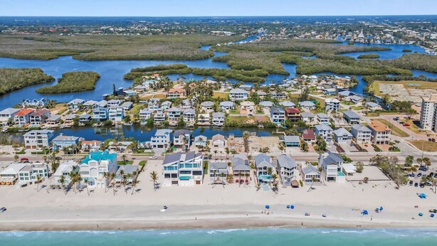 Un quartier résidentiel situé sur la côte, avec des propriétés donnant sur la plage, un port de plaisance et un ensemble dense de maisons.