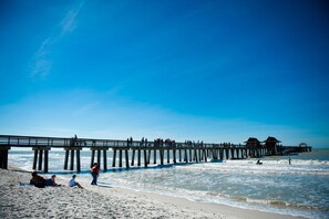 A pier extending into the ocean with people walking and sitting on it.