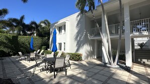Une cour avec des espaces de détente en plein air, des palmiers et un bâtiment blanc doté de balcons.