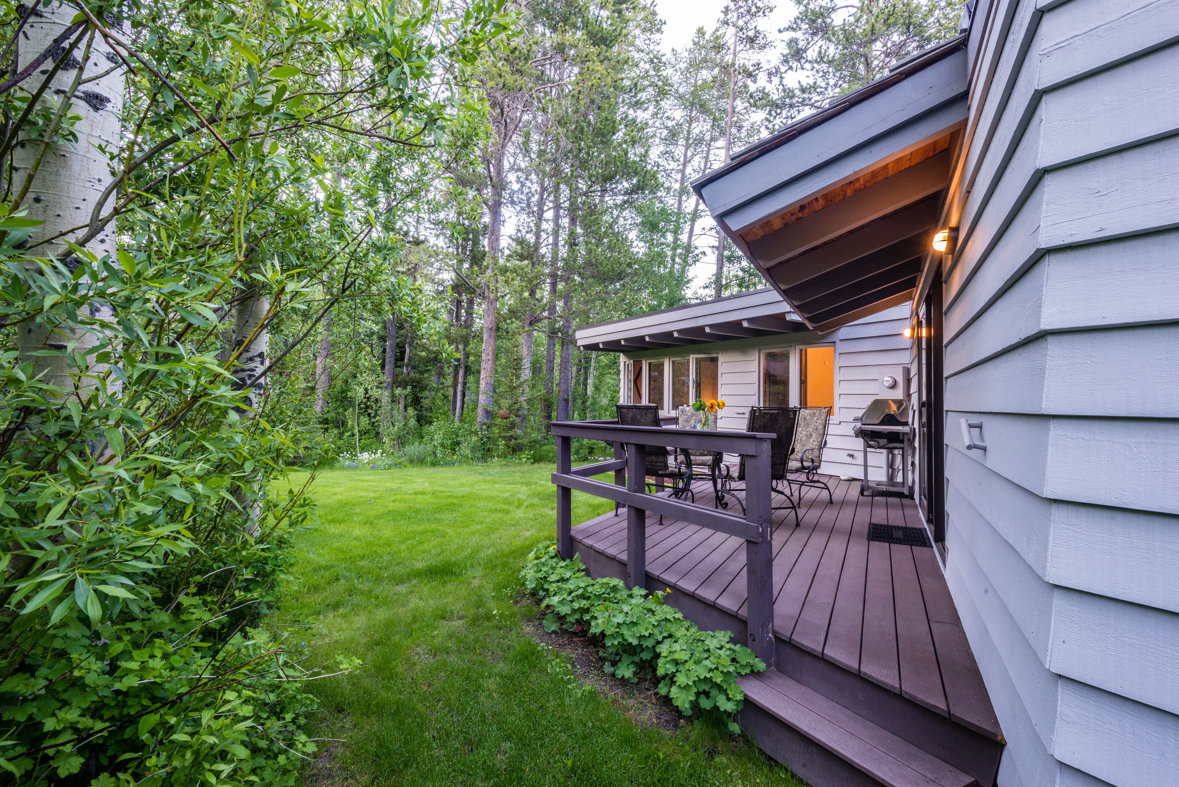 A wooden deck with outdoor furniture, a grill, and a small porch area.