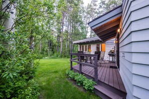A wooden deck with outdoor furniture, a grill, and a small porch area.