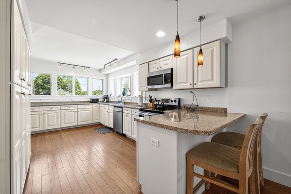 A modern kitchen with white cabinetry, a central island, and pendant lighting.