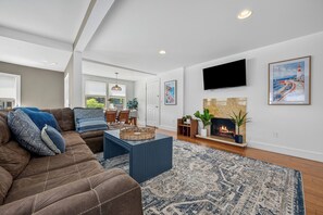 A modern living room with a fireplace, a flat-screen TV, and a large window. - Private, 1st Floor Cottage, 5 Minute Walk to Beach- Perfect for Families! (Old Orchard Beach)
