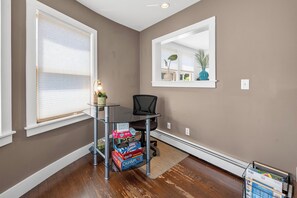 A room with a desk, chair, and a window with blinds.