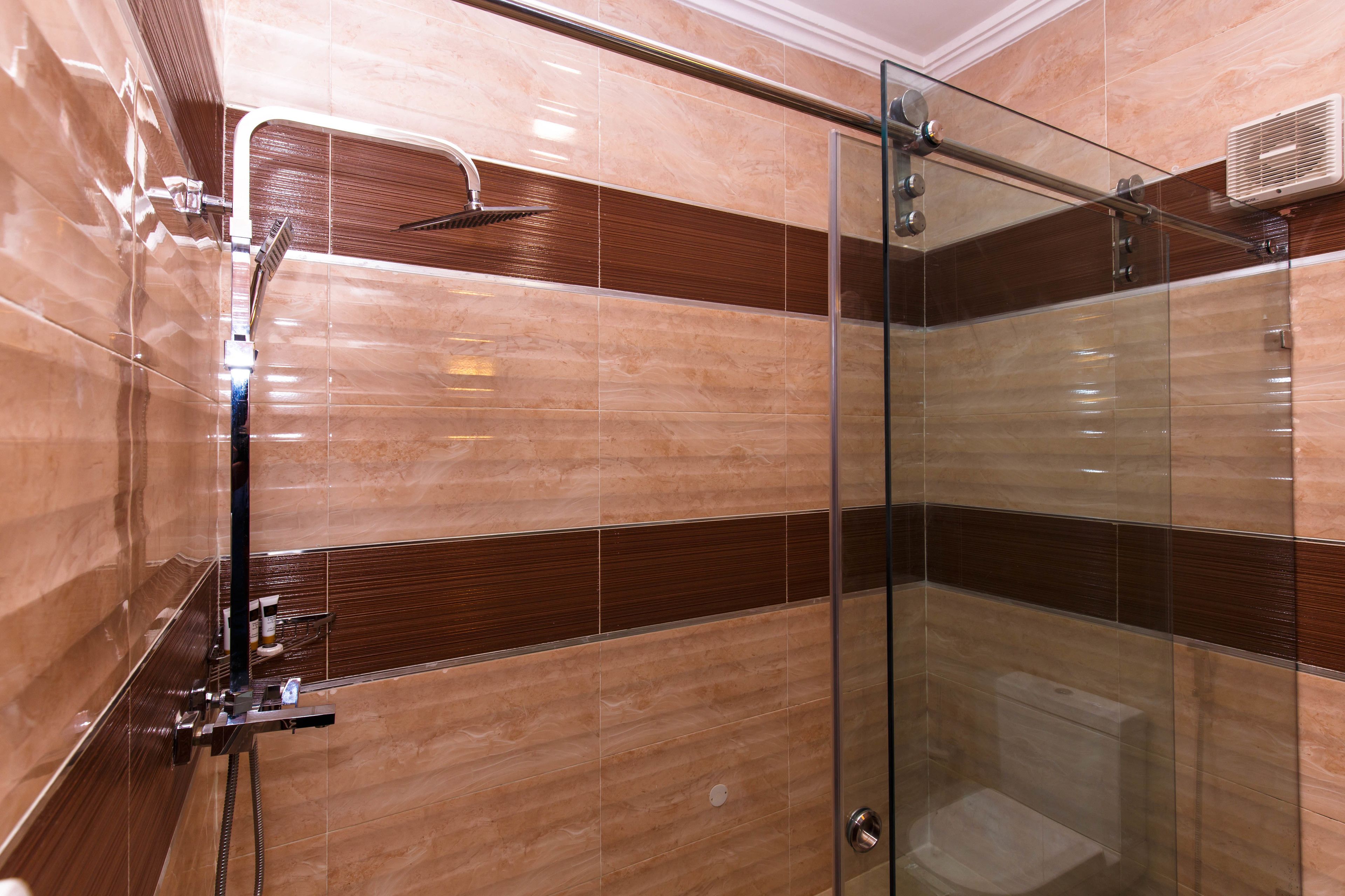 Un baño moderno con cabina de ducha de vidrio, un cabezal de ducha manual y un perchero en la pared.