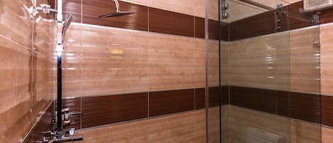 Un baño moderno con cabina de ducha de vidrio, un cabezal de ducha manual y un perchero en la pared.