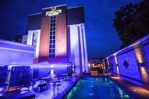 A hotel with a pool area, outdoor seating, and a prominent entrance with illuminated signage. - Joygate Hotel & Suites (Lagos)